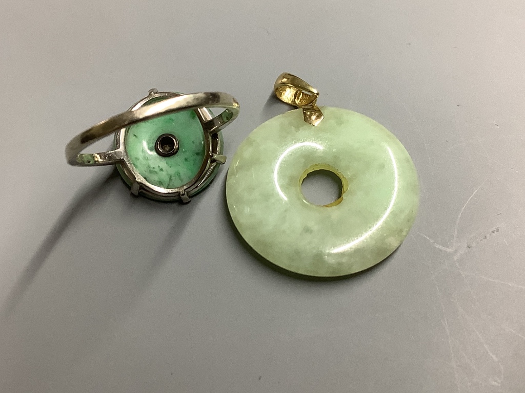 A 9ct white metal, jade and diamond set disc ring, size M, gross 2.1 grams and a 14k mounted jade disc pendant, gross 3.8 grams.